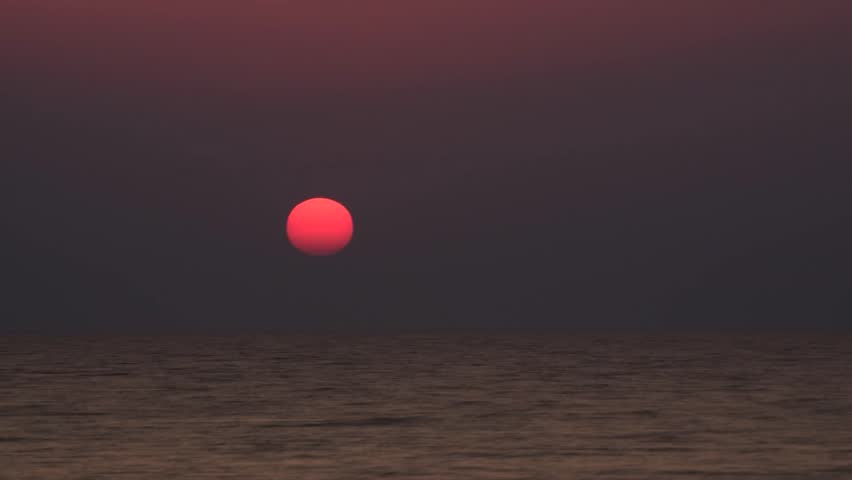 Time lapse of beautiful sunrise at ocean or sea with sun disk quickly going up over water surface in cloudless sky