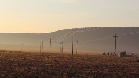 Endurance riders ride horses across a field at sunrise. The Free State, South Africa.