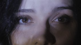Close up eyes of a young woman watching a video or film on TV or a computer monitor. Reflection on her face