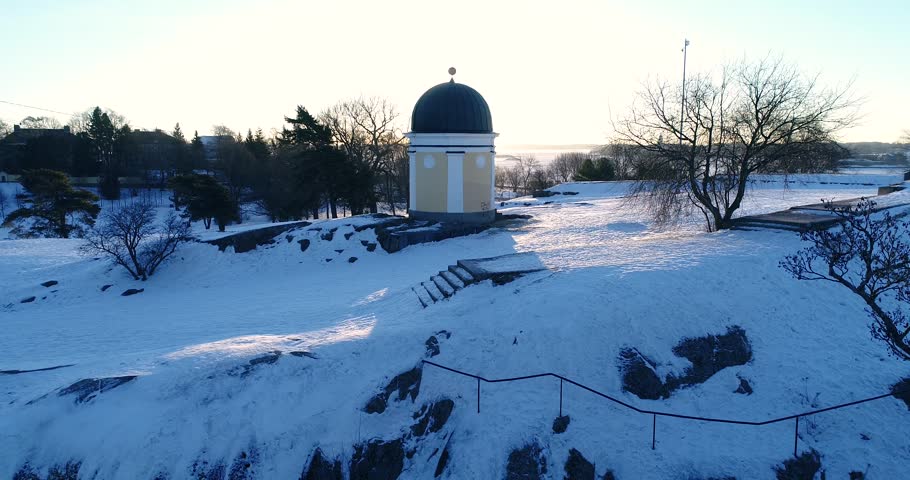 Aerial winter sunrise. Drone rising and sun reviling behind observatory. Kaivopuisto, Helsinki, Finland