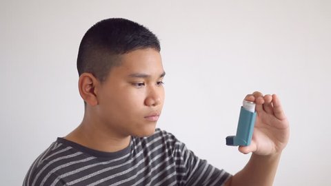 Asthma - Asian teenage boy using an inhaler for asthma and respiratory diseases. Inhalation treatment of respiratory diseases. Allergy and bronchial asthma concept. 