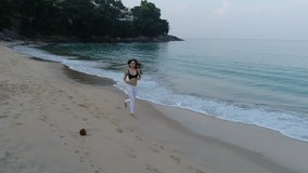 Aerial drone view of beautiful young girl jogging in the morning on the sandy beach - video in slow motion