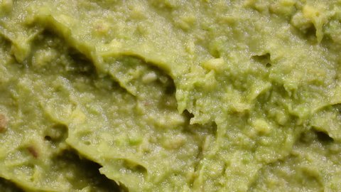 Extreme closeup top view of avocado smash rotating in 4K. Traditional tasty sauce guacamole.