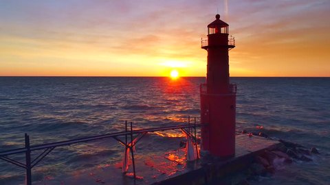 Beautiful moving aerial view of iconic lighthouse with waves at sunrise.

