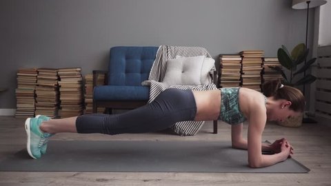 Fitness woman doing plank exercise on mat at home