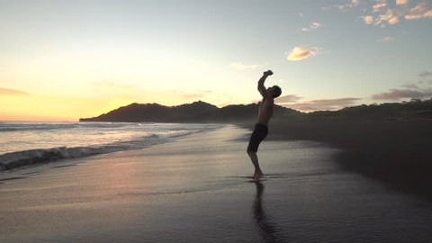 Slow motion backflip and flip combo shot on black sand beach at sunset.