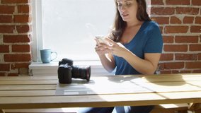 Slow motion of woman sending a text with professional camera on table