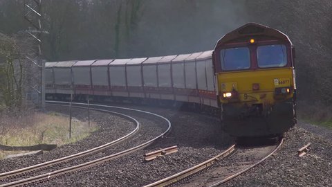 A long goods train pulled by a diesel locomotive. Coming towards the camera.