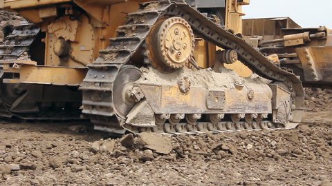 Heavy earth mover, bulldozer machine is leveling construction site.
View on bulldozer, crawler while he is moving and leveling ground at building site. 