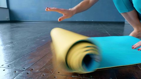 A woman unfolds a rug for practicing yoga in the studio.