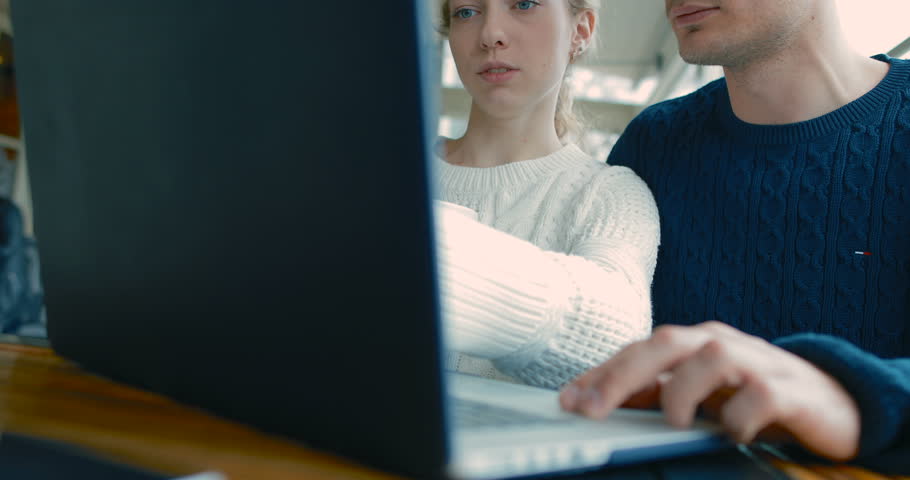 Young people chatting in a cafe. Guys have a nice conversation. before them on the desk is a laptop. in slow motion