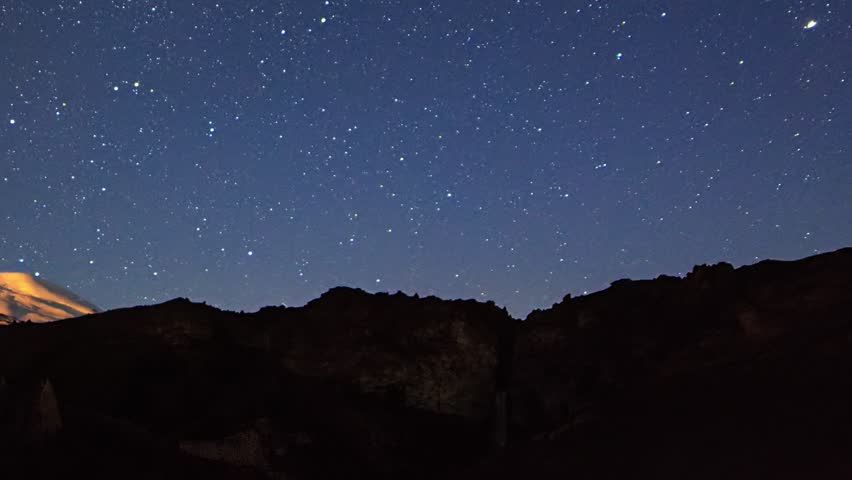 Stars draw fading lines and clouds over Mount Elbrus. Night landscape. Russia. Traces in the form of a line from the stars
