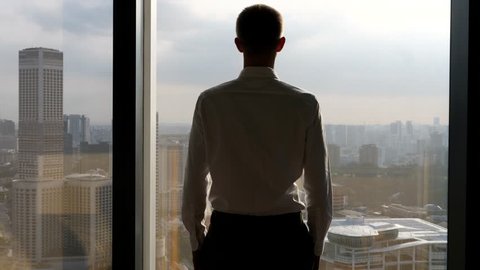 Businessman Looking At City From Office