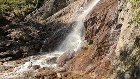 Mountain waterfall in Siberia. A dynamic video made on a journey. Bright sunny day. Conservation of natural phenomena.
