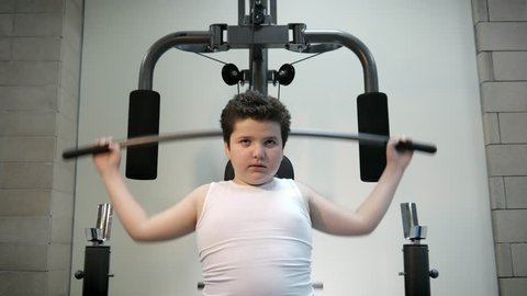 thick angry kid boy trains in gym fat burning.will power children concept overweight tenacity purpose