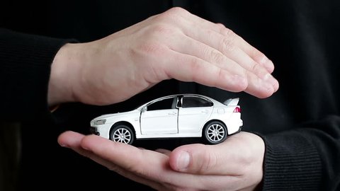 A man holding a small car. The concept of car insurance, security systems, leasing and car purchases
