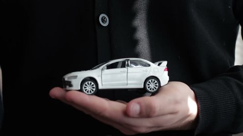 A small car in the hands of a man. concept: car insurance, car sales, garages, rental and alarm systems