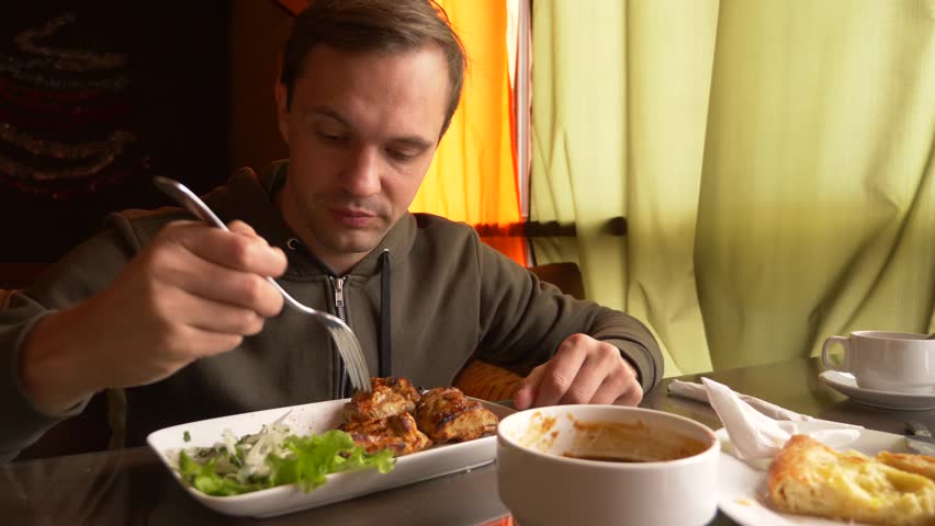 The man in the restaurant eats hot meat with a fork, 4k, slow-motion shooting | Shutterstock HD Video #1009249469