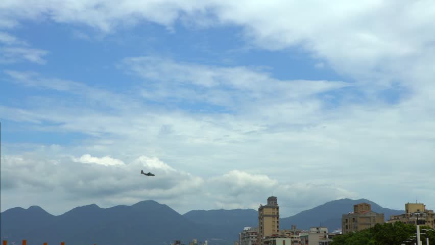 4k View of military plane flying low over the buildings in Taipei city. Airplane fly above skyscrapers. Plane in the air up houses an urban area in Taiwan. Flight trip with blue sky-Dan