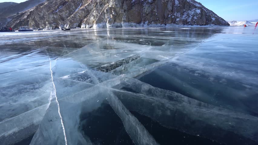 Mountain reflection blue clear transparent ice iceberg details. Cinematic deep crack unique pattern. Lake Baikal Russia.  North Arctic Sea ocean. Winter season. From ground close-up