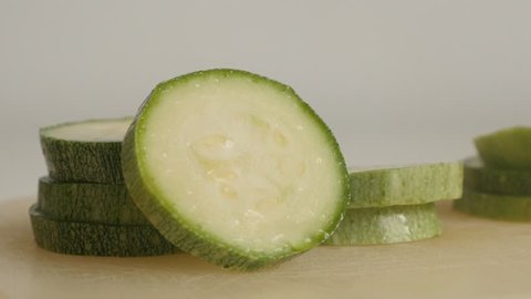 Organic zucchini slices on pile. Close-up of Pepo cylindrica on cutting board slow tilt