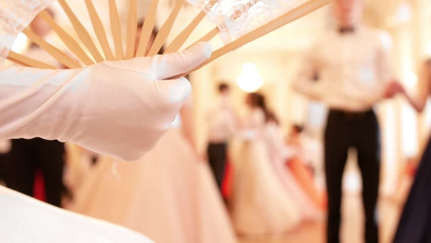 Vintage fan in the hands of young lady, on a background dancing couples
