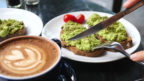 Close Up Of Female Hands Cutting Avocado Toast While Having Breakfast With Coffee ஸ்டாக் வீடியோ