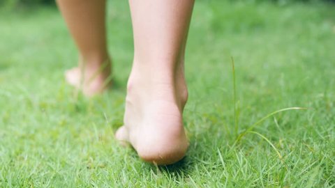 Young Woman Walking Bare Feet on Green Grass Field. 4K, Slowmotion.