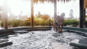 Young man jumps in to the hot tub during sunset an outdoor spa center. slow motion. 1920x1080