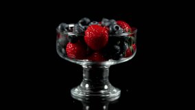 strawberry with blueberries in a glass on a black background rotates