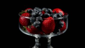 close-up. strawberry with blueberries in a glass on a black background rotates