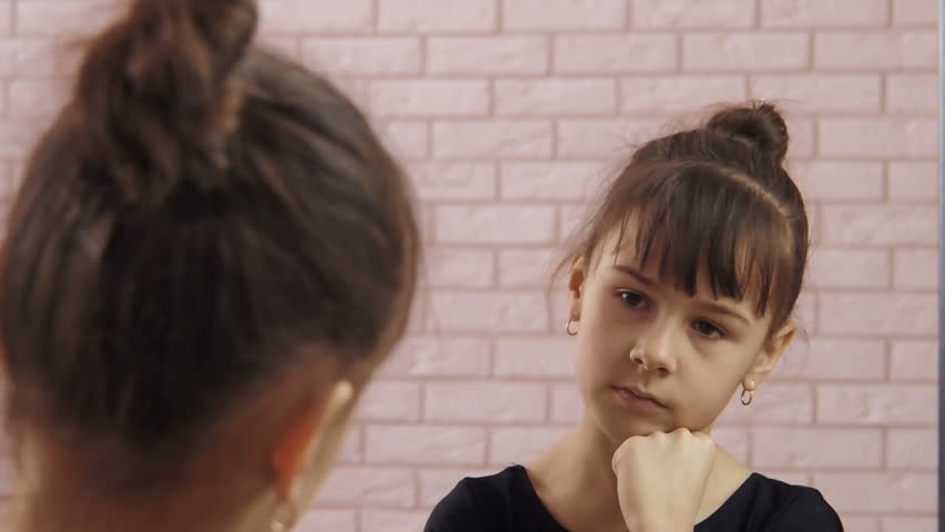 The child looks in the mirror. A little girl is looking at a reflection in a mirror.