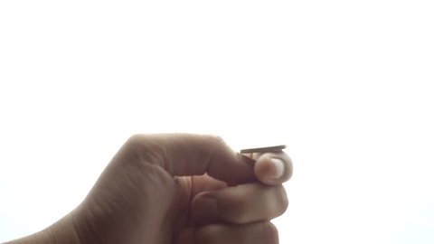Man tossing a coin on white background in slow motion