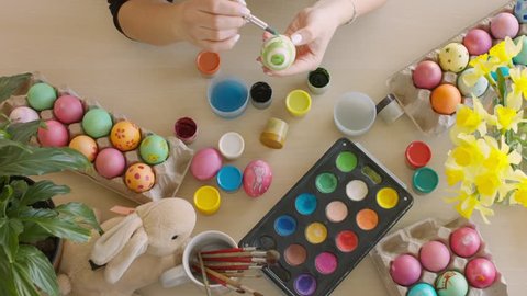 Colorful Easter eggs on the table. Woman colored eggs for Easter with brush.