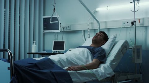 Terminally Ill Male Patient Lies on a Bad In the Hospital. Melancholy and Exhausted Patient in the Palliative Care Ward. Shot on RED EPIC-W 8K Helium Cinema Camera.