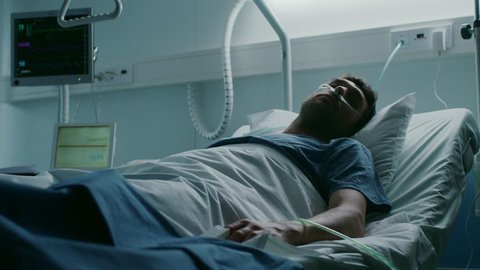 In the Hospital, Terminally Ill Man Suffers While Lying on the Bed. Young Man in Palliative Care Ward. Shot on RED EPIC-W 8K Helium Cinema Camera.