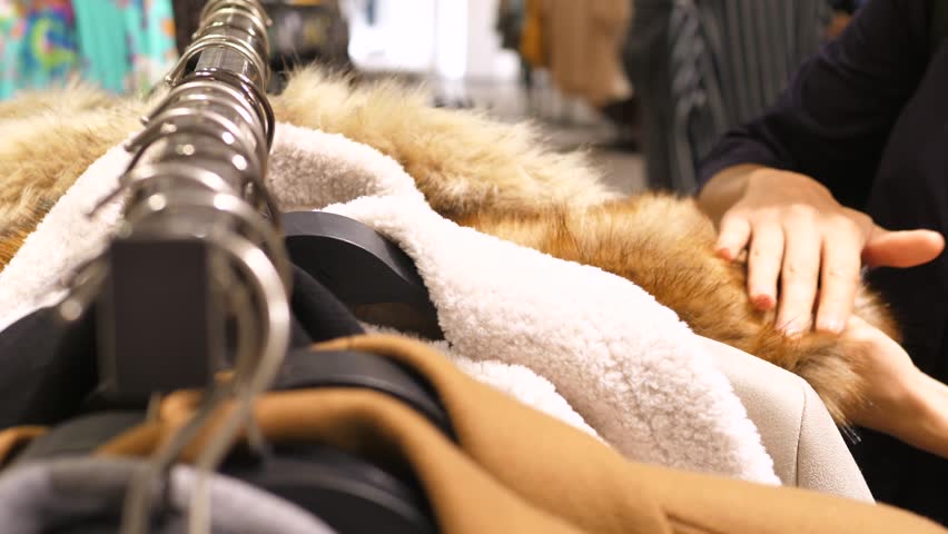 Female Customer Shopping For Clothes Choosing Coat From Fake Fur In Clothing Store Royalty-Free Stock Footage #1009296629