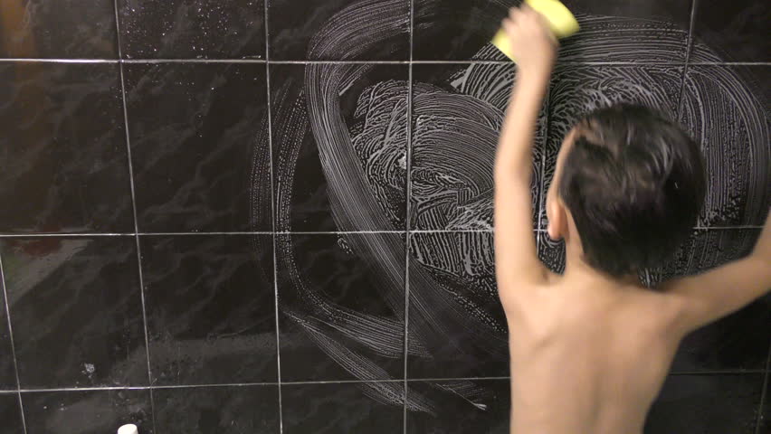 the boy in the bathroom does the cleaning, the little boy washes the tile