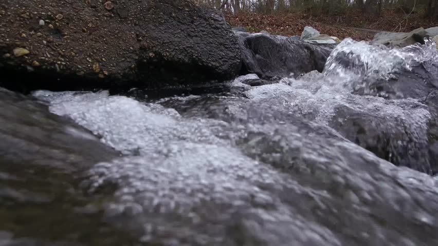 Small stream with bubbles flows over rocks