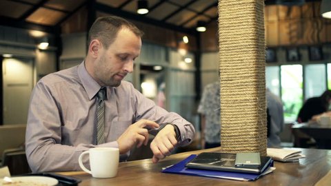 Young businessman with smartwatch sitting in cafe
