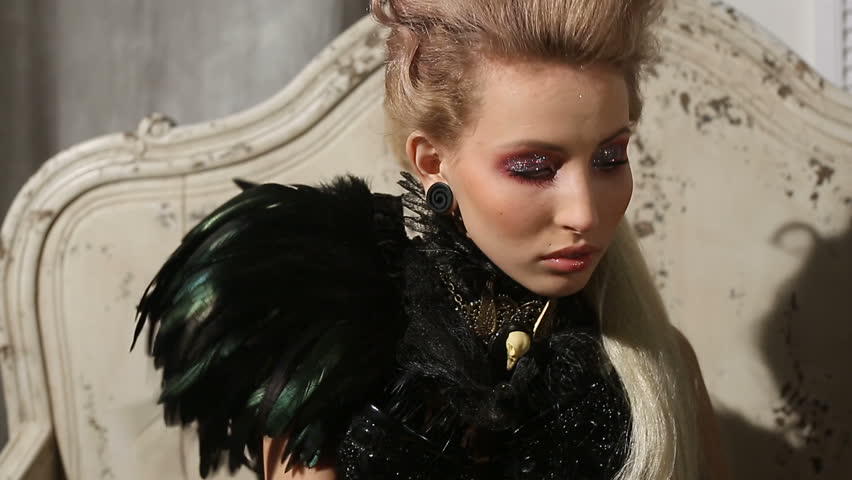 Close-up portrait of beautiful gothic lady. Woman in black feathers collar fantasy look for Halloween. Beautiful gothic lady vampire