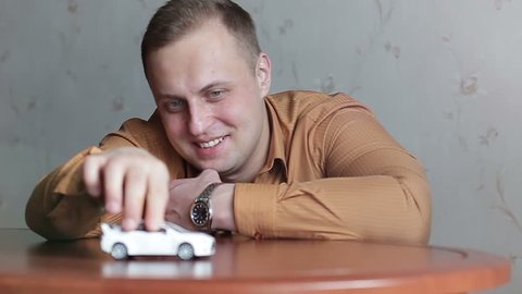 Adult man playing with a children's toy car. Concept of nostalgia for childhood