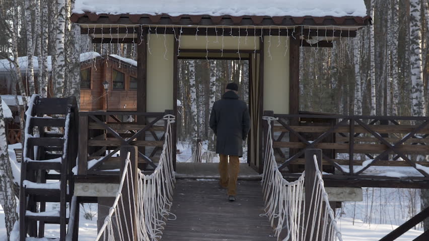 Man going on the bridge and standing on wooden building