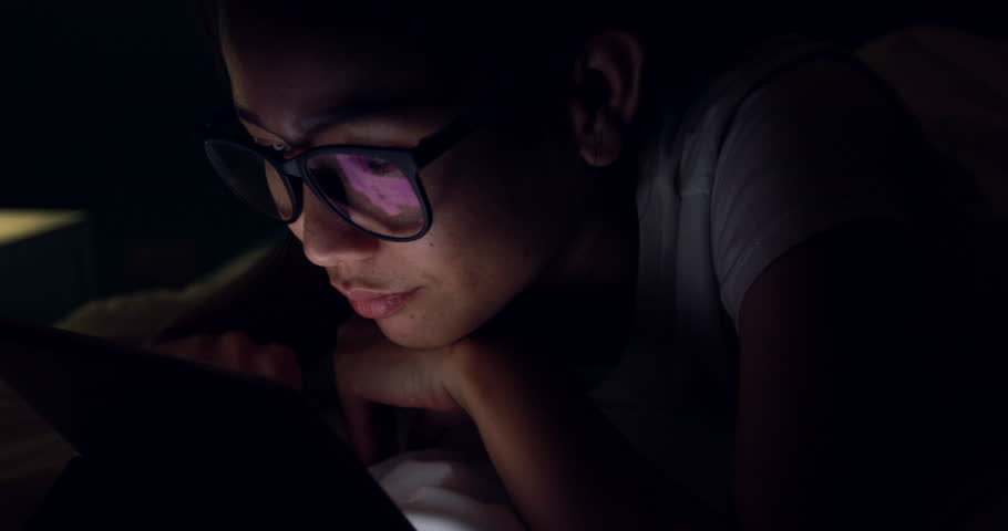 Young asian woman playing with a cellphone or smartphone on a bed. night