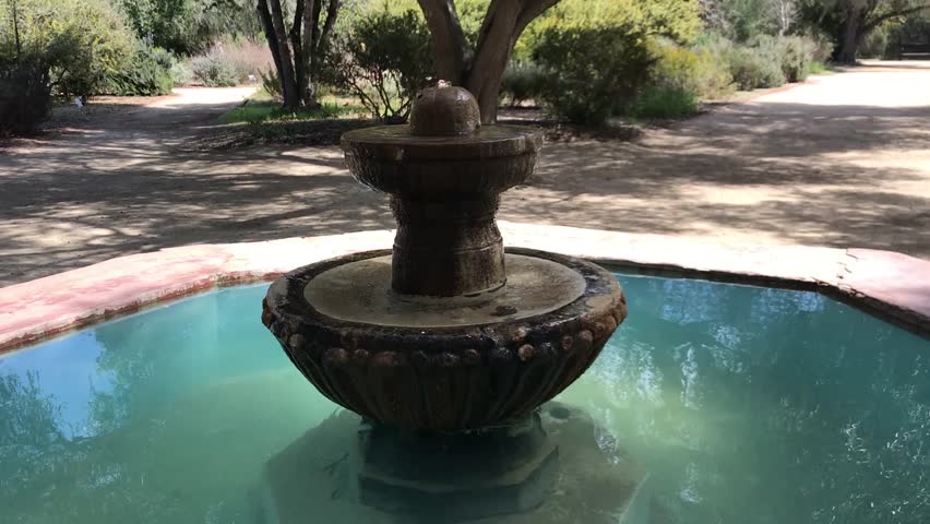 Beautiful Spanish-style courtyard fountain with olive trees in the background