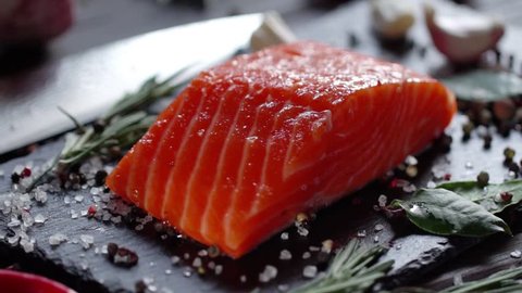 Preparation of salmon steak. Spice and salt sprinkled on a raw piece of salmon. Camera moves around the object. Slow motion 120 fps video.
