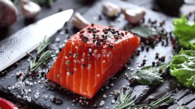 Raw salmon steak with spices and herbs. Camera moves around the object. 4K video.
