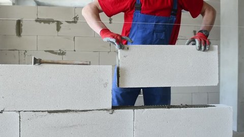 bricklayer builder working with autoclaved aerated concrete blocks. Walling