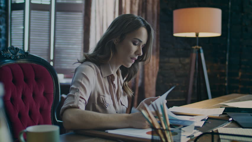 Worried business woman thinking in office at evening. Focused businesswoman working with document. Female worker learning bad business statistic. Concentrated woman reading papers in office | Shutterstock HD Video #1009353707