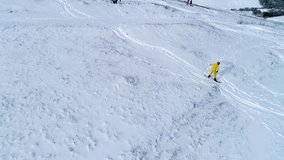 Snowboarder riding down the slope on a snowy field, 4k video clip. Aerial shot of snowboarding